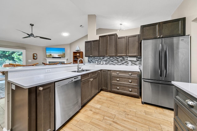 kitchen featuring sink, kitchen peninsula, appliances with stainless steel finishes, light wood-type flooring, and vaulted ceiling