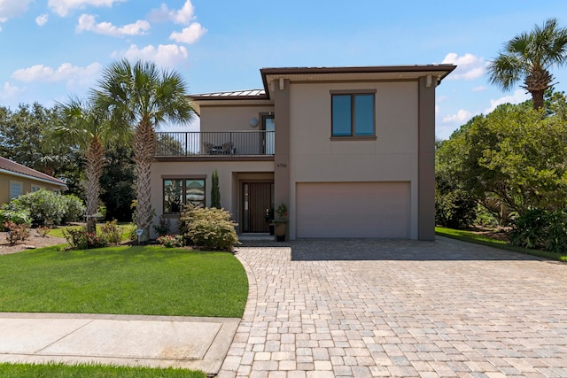 view of front facade featuring a balcony, a front yard, and a garage