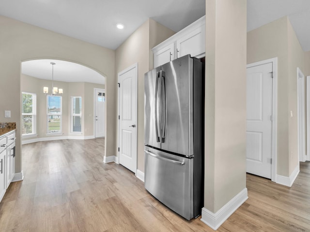 kitchen with white cabinets, stainless steel refrigerator, light hardwood / wood-style flooring, and a chandelier