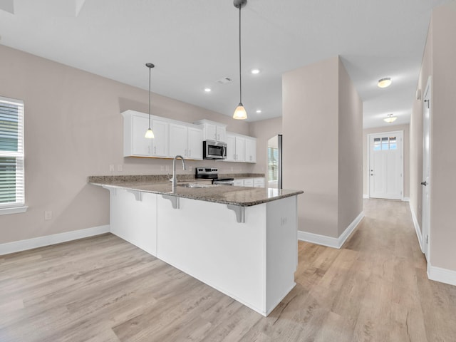 kitchen featuring white cabinetry, kitchen peninsula, stainless steel appliances, light hardwood / wood-style flooring, and decorative light fixtures