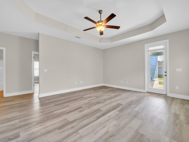 empty room featuring ceiling fan, a raised ceiling, and light hardwood / wood-style floors