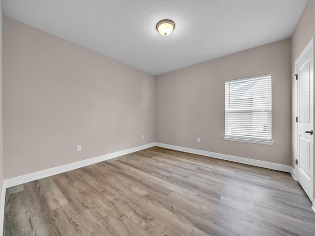 unfurnished room with a textured ceiling and light hardwood / wood-style floors