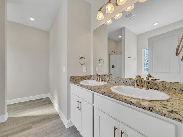 bathroom with walk in shower, vanity, and wood-type flooring