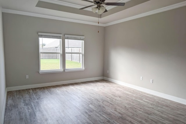 empty room with ornamental molding, light hardwood / wood-style flooring, a tray ceiling, and ceiling fan