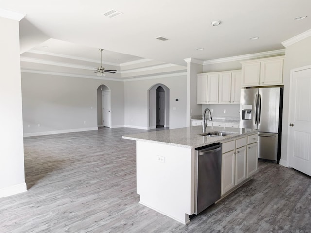 kitchen featuring a center island with sink, crown molding, appliances with stainless steel finishes, and a tray ceiling