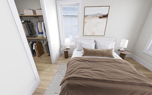 bedroom with a spacious closet, a closet, and light wood-type flooring