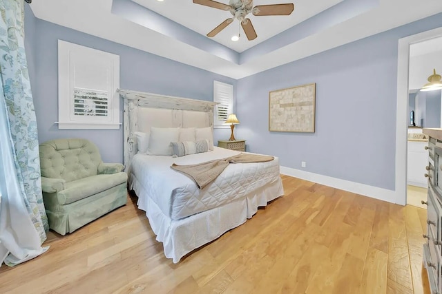 bedroom with ceiling fan, light hardwood / wood-style floors, and a raised ceiling