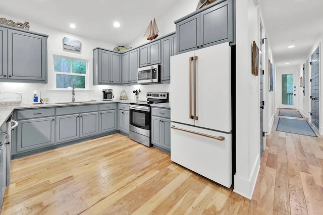 kitchen featuring appliances with stainless steel finishes, light hardwood / wood-style floors, gray cabinets, and sink