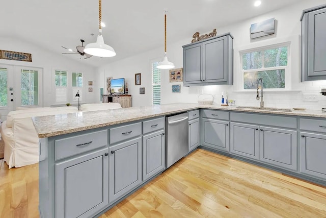 kitchen with sink, vaulted ceiling, kitchen peninsula, stainless steel dishwasher, and hanging light fixtures