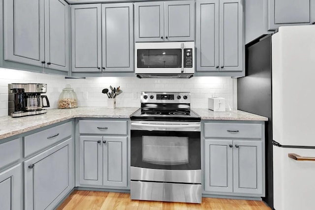 kitchen with refrigerator, backsplash, stainless steel electric range oven, and light stone countertops