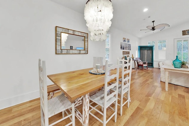 dining space with hardwood / wood-style floors, vaulted ceiling, and ceiling fan with notable chandelier