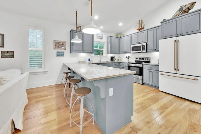 kitchen featuring a kitchen breakfast bar, appliances with stainless steel finishes, kitchen peninsula, pendant lighting, and sink