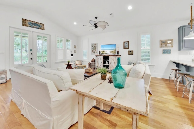 living room with lofted ceiling, french doors, ceiling fan, and light wood-type flooring