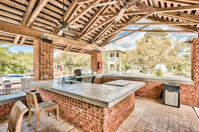 view of patio with an outdoor kitchen, ceiling fan, area for grilling, an outdoor wet bar, and a gazebo