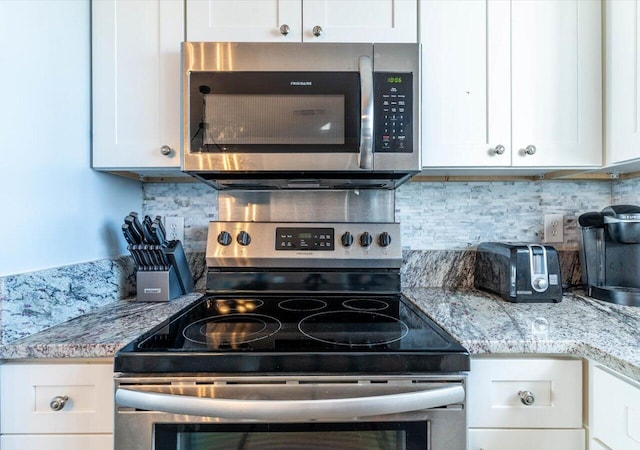 kitchen featuring white cabinets, stainless steel appliances, light stone countertops, and tasteful backsplash