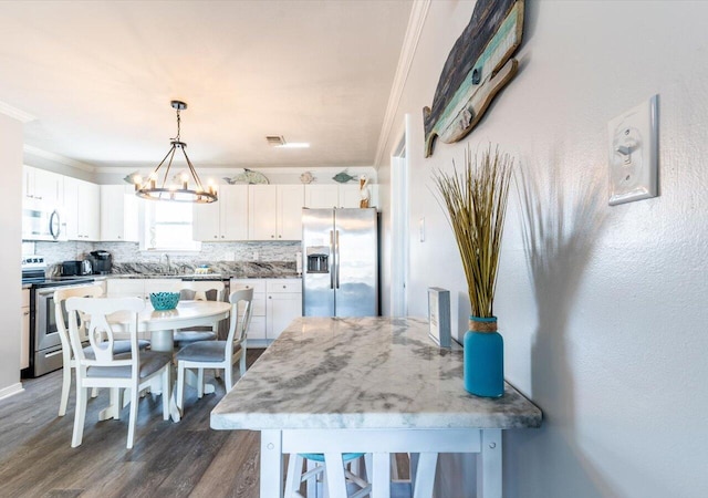 kitchen featuring appliances with stainless steel finishes, white cabinetry, dark hardwood / wood-style floors, and tasteful backsplash