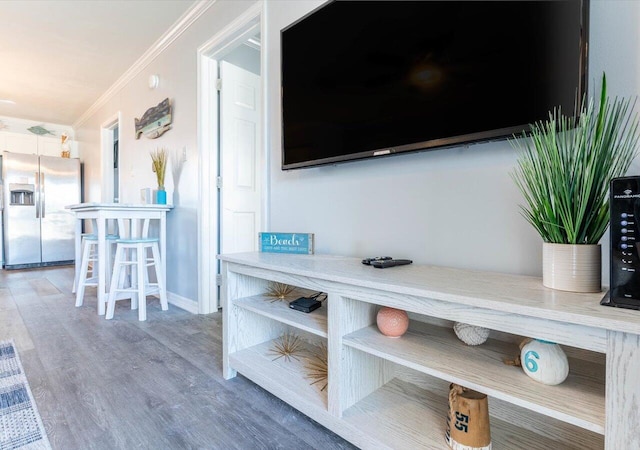 interior details featuring ornamental molding, hardwood / wood-style floors, and stainless steel fridge with ice dispenser