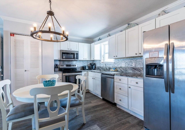 kitchen with appliances with stainless steel finishes, white cabinetry, an inviting chandelier, decorative light fixtures, and ornamental molding