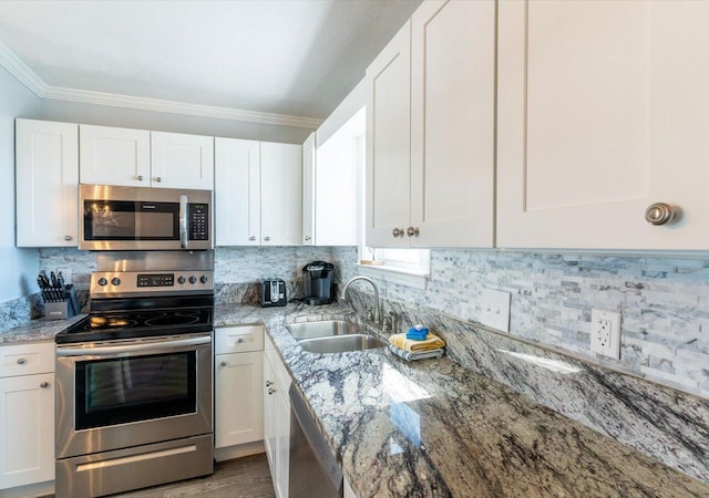 kitchen featuring appliances with stainless steel finishes, crown molding, sink, and white cabinetry