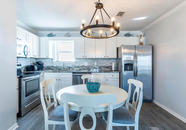 kitchen with appliances with stainless steel finishes, white cabinetry, pendant lighting, and a chandelier