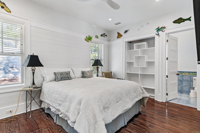 bedroom with ceiling fan, ensuite bathroom, and dark wood-type flooring