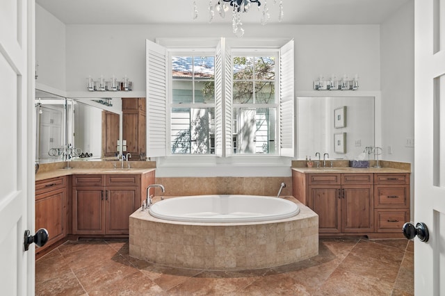 bathroom featuring vanity, a relaxing tiled tub, and an inviting chandelier