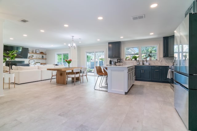 kitchen with tasteful backsplash, a kitchen bar, a kitchen island, gray cabinetry, and stainless steel fridge