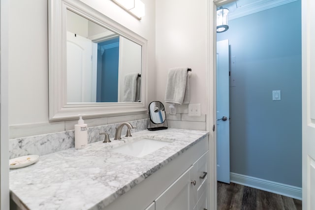 bathroom with ornamental molding, vanity, hardwood / wood-style floors, and tasteful backsplash