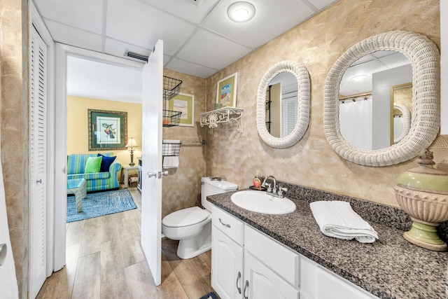 bathroom with vanity, a drop ceiling, hardwood / wood-style floors, and toilet