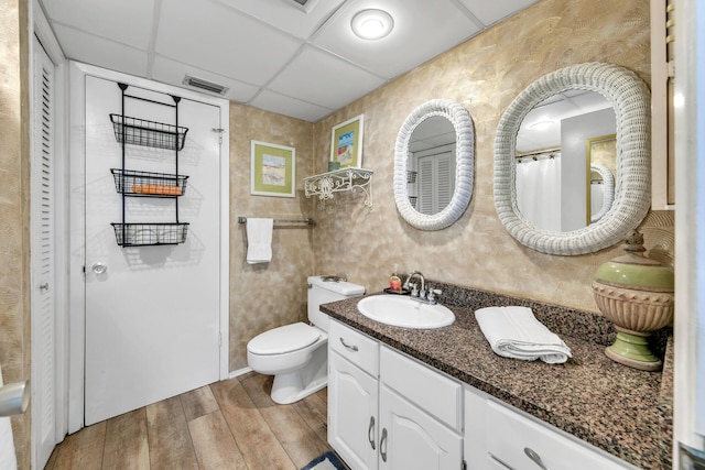 bathroom with vanity, hardwood / wood-style floors, toilet, and a paneled ceiling