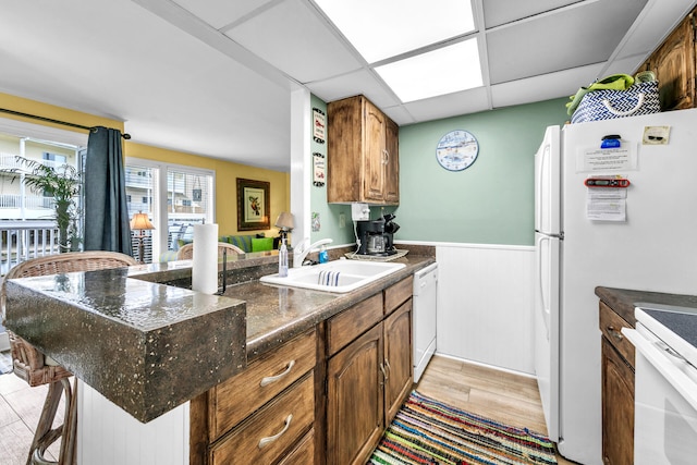 kitchen featuring white appliances, kitchen peninsula, light wood-type flooring, a paneled ceiling, and sink