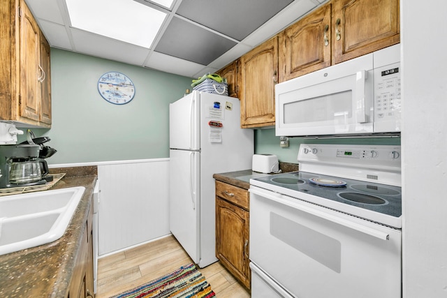 kitchen with light hardwood / wood-style floors, white appliances, sink, and a drop ceiling