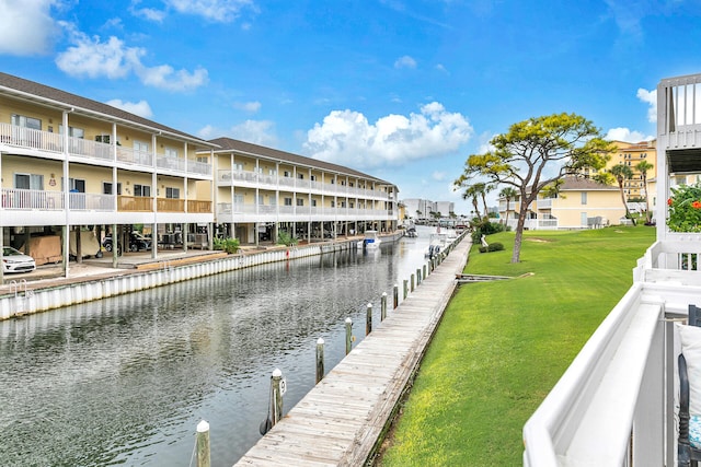 view of dock featuring a lawn, a water view, and a balcony