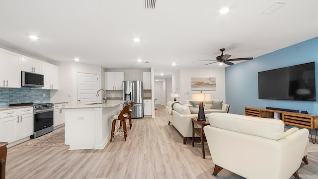 living room with ceiling fan, light wood-type flooring, and sink