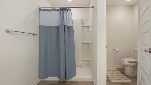 bathroom featuring hardwood / wood-style floors, toilet, and a shower with shower curtain