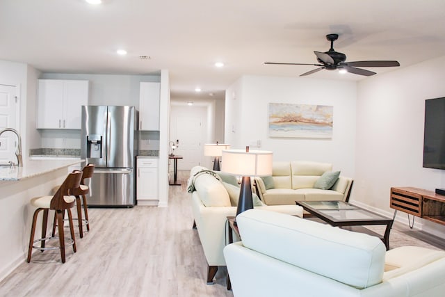 living area featuring recessed lighting, a ceiling fan, baseboards, visible vents, and light wood-style floors