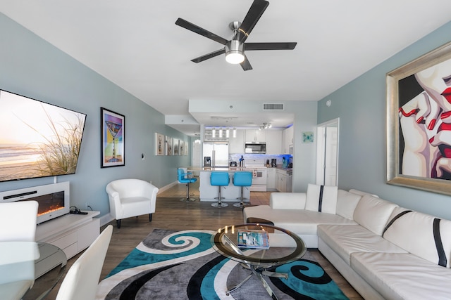 living room with ceiling fan and dark wood-type flooring