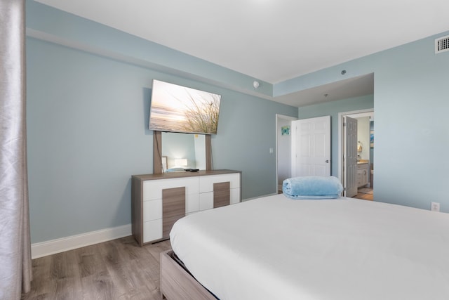 bedroom with wood-type flooring and ensuite bathroom