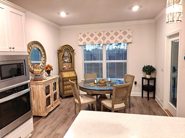 dining space with light hardwood / wood-style flooring, a chandelier, and crown molding