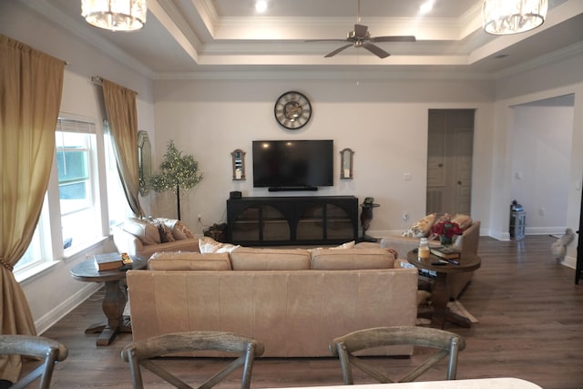 living room featuring ceiling fan with notable chandelier, dark hardwood / wood-style floors, a tray ceiling, and crown molding