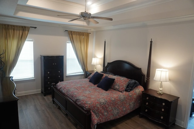 bedroom with ornamental molding, a tray ceiling, ceiling fan, and dark wood-type flooring