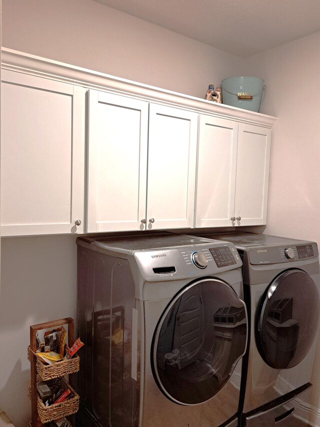 washroom with wood-type flooring, cabinets, and washer and dryer