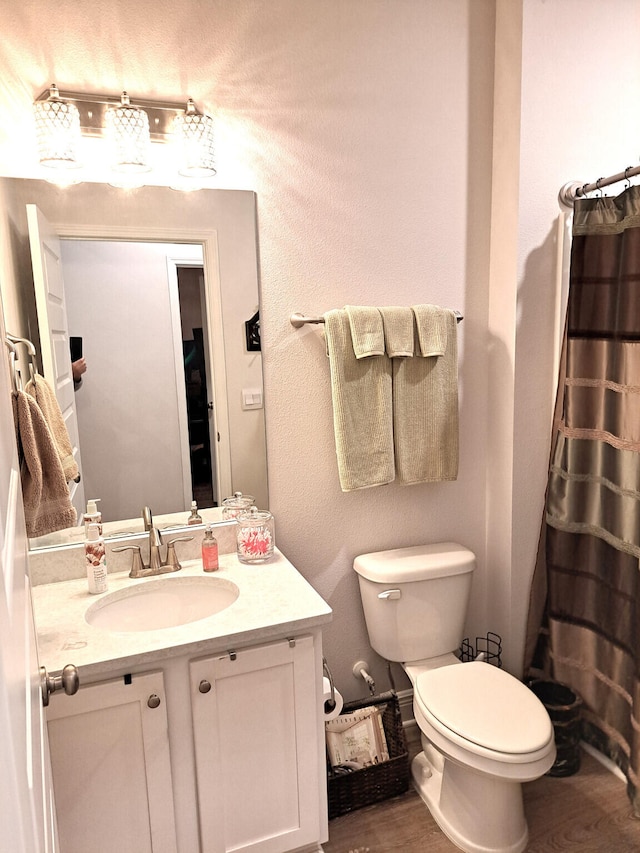 bathroom with wood-type flooring, vanity, toilet, and curtained shower