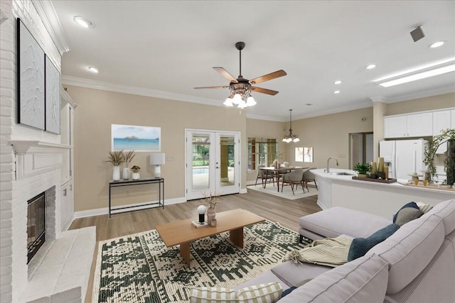 living room with a fireplace, ornamental molding, and light hardwood / wood-style flooring