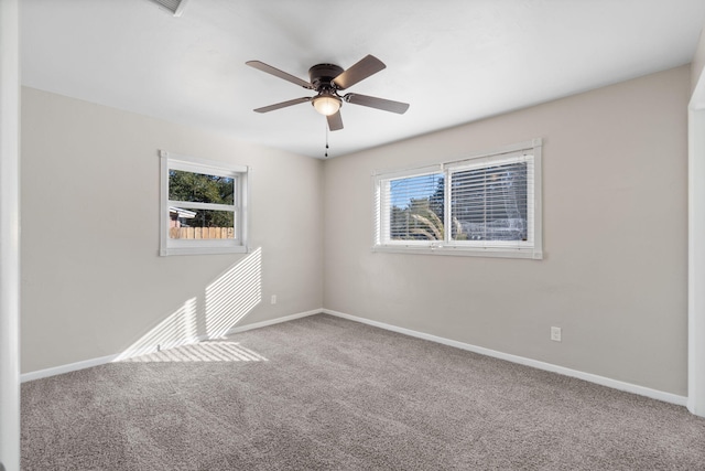 carpeted spare room featuring plenty of natural light and ceiling fan