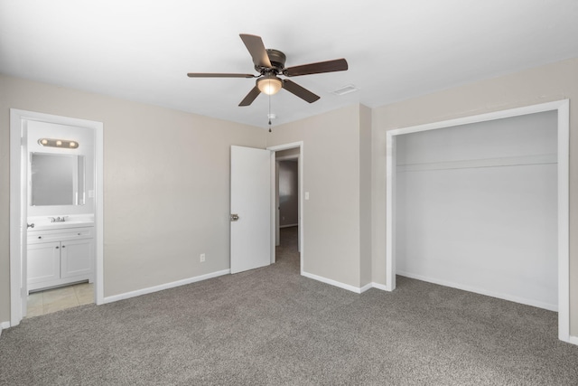 unfurnished bedroom featuring ceiling fan, ensuite bathroom, a closet, and light carpet