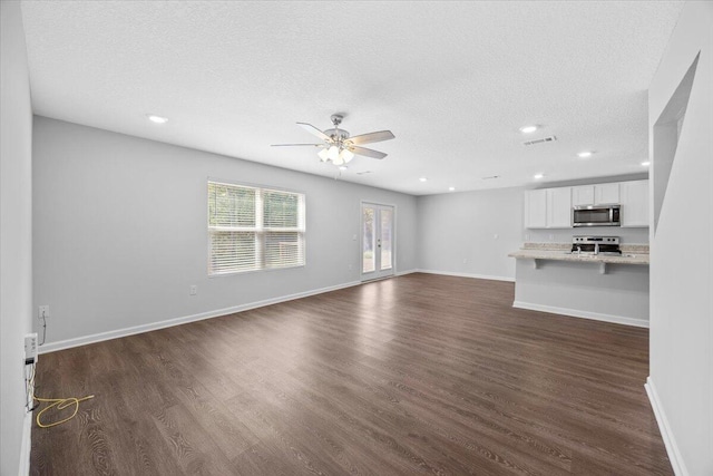 unfurnished living room featuring ceiling fan, dark hardwood / wood-style flooring, and a textured ceiling