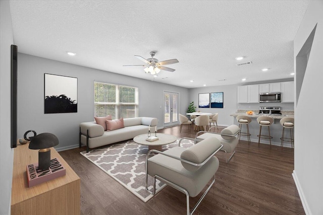 living room featuring a textured ceiling, dark hardwood / wood-style floors, and ceiling fan