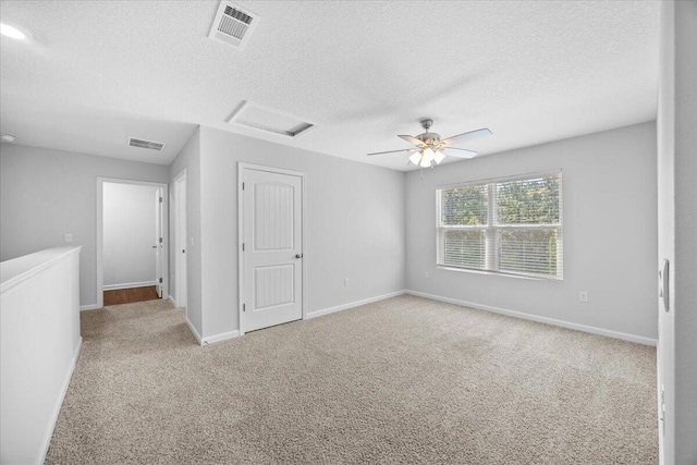 carpeted spare room with ceiling fan and a textured ceiling