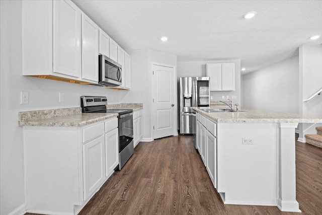 kitchen featuring a center island with sink, sink, dark hardwood / wood-style flooring, white cabinetry, and stainless steel appliances